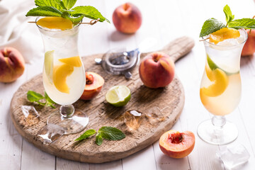 Refreshing peach mojitos on a rustic wooden board against a bright background.