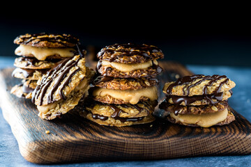 Stacks of chocolate and caramel lace cookies, against a dark background.