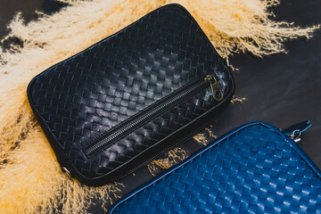 Black leather zip wallet placed on dried grass, black background, arranged with promotional images.