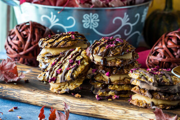Stacks of chocolate and caramel lace cookies on a rustic wooden board.