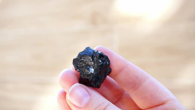 Sparkly black shungite mineral stone on natural light in hand