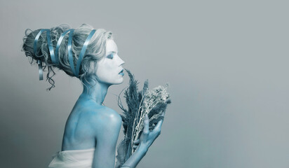 Pretty young Snow Queen woman actress with stage makeup and hairstyle on blue banner background....