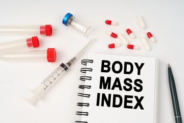 On the table are pills, injections, a syringe and a notepad with the inscription - BODY MASS INDEX