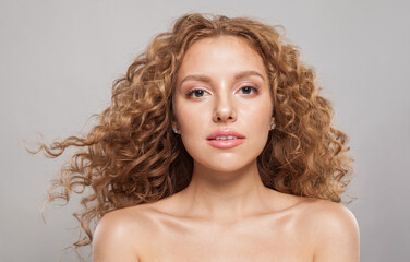 Cheerful redhead female model with wavy hairstyle. Pretty young woman with healthy curly hair...