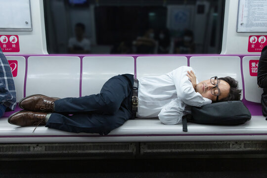 A middle-aged man sleeping in a seat in a subway car