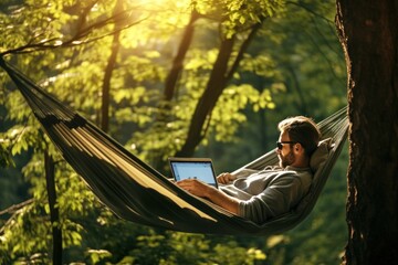 portrait of a European man lying in a hammock with a laptop in nature. remote work - obrazy, fototapety, plakaty