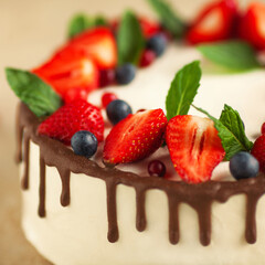 Bakery, candy shop concept. Close-up image of amazing wedding cake with fresh berries and dark chocolate topping. Natural light. Indoor shot