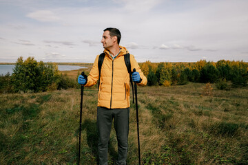 a tourist with hiking equipment walks through the field in autumn.Hiking in wild places