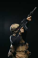 Photo of a confident and courageous military man on a dark isolated background in a camouflage...