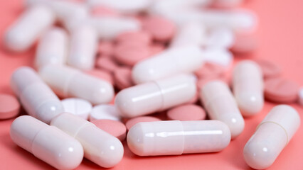 Many pink and white pills in capsules. Medical treatment with medicine, vitamins or nutrition supplements. Woman health. Textured background. Close up, selective focus