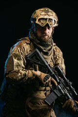 Photo of a confident and courageous military man on a dark isolated background in a camouflage...