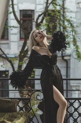Elegant blonde woman in luxury black silk robe with a feathers. Woman wardrobe, perfection in every...