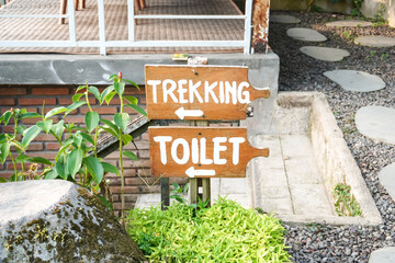 Signposts with directions to the Trekking Area and To the Toilet. White colored toilet signage...