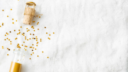 Champagne bottle with pours golden sparkling stars confetti and fly cork on white fur background,...