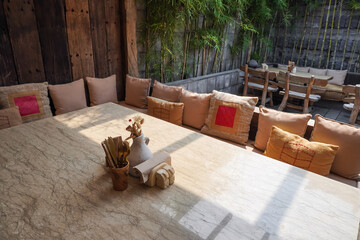 Indoor Cafe tables and chairs set made of wood and rattan. Natural interior design concept for tropical hotel, resort, villa, restaurant and cafe. Burlap sackcloth covered sofa and square pillows.