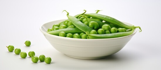 Fresh healthy summer cooking with green peas in a white bowl isolated with a fresh pea pod