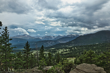 mountainous landscape with trees and grass in a cloudy sky.