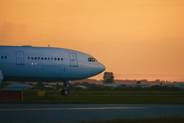 Airplane taxiing to runway for take off. Airport at golden sunset..