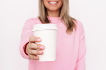 Cropped shot of a young blonde smiling woman in a pink sweatshirt holding out her hand with white...