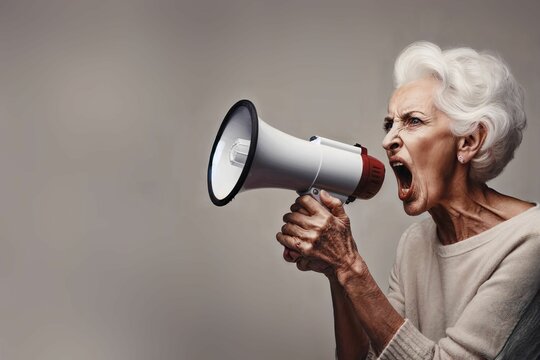 Senior woman yelling on a megaphone on a solid background