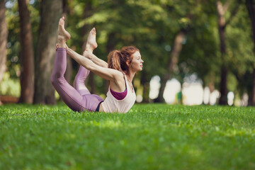 Fit caucasian woman practising yoga in a summer park