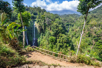 Fototapeta na wymiar The Sekumpul Waterfall, a large waterfall in the middle of the jungle that falls into a deep green gorge. Trees and tropical plants at Bali's highest waterfall.