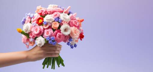 Hand with flower bouquet  from designer parts, constructor. Valentines Day or mothers Day. Ecological trend of gifts. Trendy gift 2024. Banner.