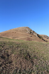 A grassy hill with a hill in the background
