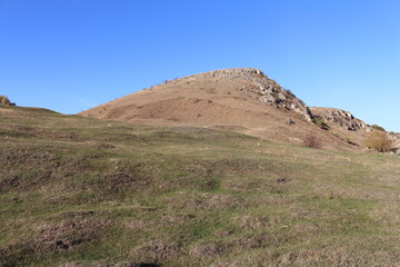 A grassy hill with a hill in the background
