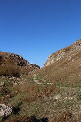 Fototapeta na wymiar A grassy hill with a rock wall and a blue sky