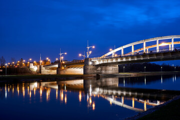 The steel structure of the road bridge over the Warta River during the night in the city of Poznan - obrazy, fototapety, plakaty