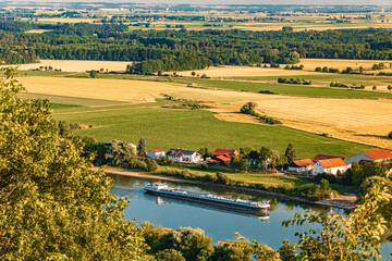 Fototapeta premium Summer view with a cargo ship and reflections at Mount Bogenberg, Bogen, Danube, Bavaria, Germany