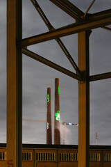 Two chimneys at night lid by colorful lights