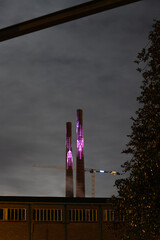 Two chimneys at night lid by colorful lights