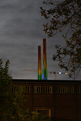 Two chimneys at night lid by colorful lights