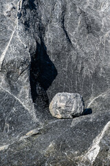 Round rock sitting in dent in large gray rock, as a nature background
