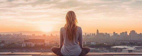 Portrait of a woman meditating on a deck overlooking a city at golden hour