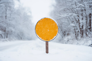 A blank road traffic sign warning of winter driving conditions on a road