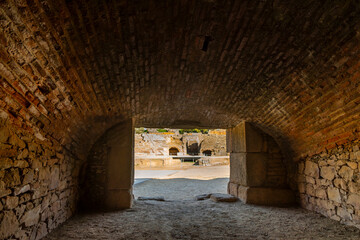 Interior with the vaulted ceiling of medieval Roman bricks of a gladiator room or beast cage with the view of the arena of the Mérida amphitheater and its entrances with arched doors.