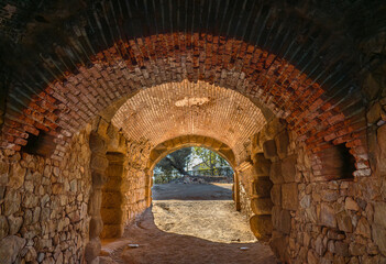 Corridor Interior of the entrance and exit of the ancient Roman Theater of Mérida, with a vaulted ceiling of brick and granite stones with the light of the dawn sun entering through the tunnel. - obrazy, fototapety, plakaty