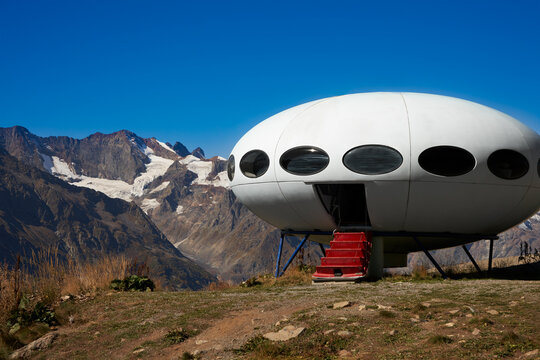 "Flying saucer" structure with an open door and a lowered ladder in the mountains