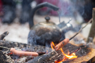 Kettle and sausages on a campfire in the forest