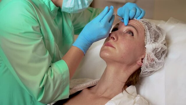 Middle aged woman getting mesotherapy treatment in face for anti aging effect by specialist in gloves in beauty salon. Dermatology procedure. Beauty injections. Plastic surgery