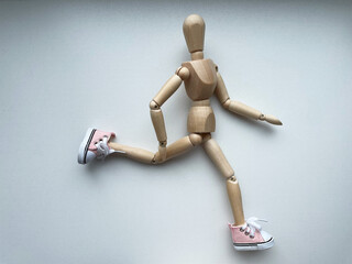 Wooden puppet running in sneakers