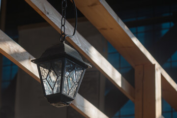 electric lantern stylized as an old street lamp hangs on a wooden beam near the railing of the...