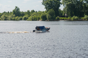a motor boat runs along the river between the banks.