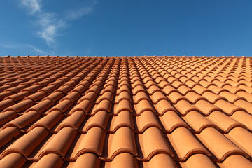 Clay tile roof close-up. New roofing made of orange clay tiles with blue sky in the background, free space for text, copy space - obrazy, fototapety, plakaty
