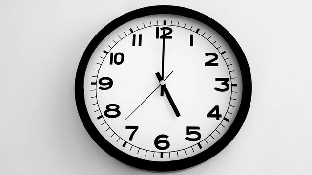 Closeup of White Clock Face on white wall clock, arrows show 17.00 or 05.00