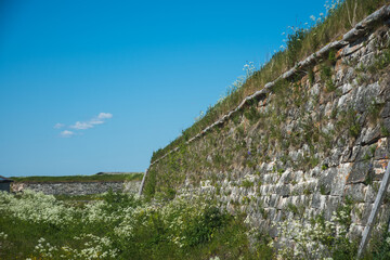 the old ancient stone wall of the fortress is overgrown with grass in places