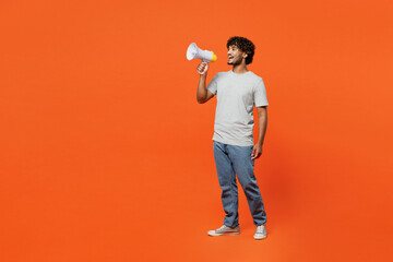 Full body shocked young Indian man he wears t-shirt casual clothes hold megaphone scream announces discounts sale Hurry up isolated on orange red color background studio portrait. Lifestyle concept. - obrazy, fototapety, plakaty